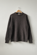 Maglione grigio melange su gruccia sfondo neutro